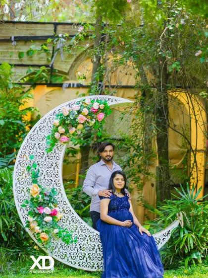 A romantic couple's portrait on the floral crescent moon prop, set in a magical garden.