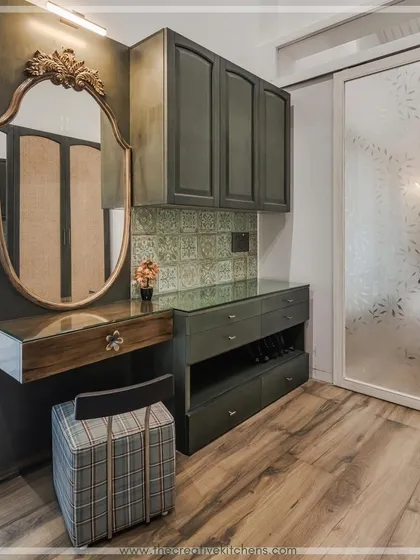 A detailed shot of the custom dressing table within the walk-in wardrobe. The pine green finish, patterned tile backsplash, and ornate mirror come together to create a personal and luxurious grooming station.