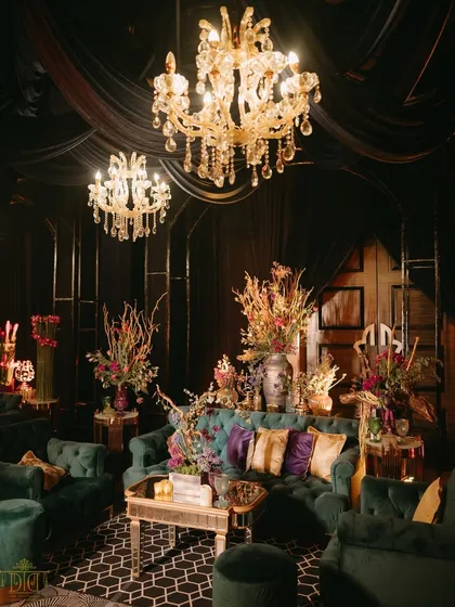 A luxurious lounge area at the masquerade sangeet. We used plush teal velvet sofas, rich floral arrangements, and ornate gold tables to create a comfortable yet opulent space for guests to relax and socialize.
