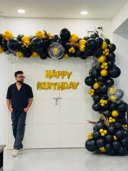 Here I am, standing proudly next to a completed black and gold balloon decoration. I oversee every detail to ensure the final result is perfect for my client's event.