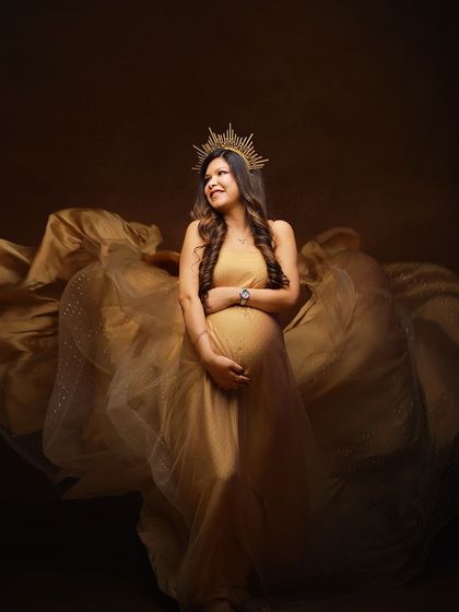 A joyful and glamorous solo shot in a golden gown. The dynamic fabric toss and happy expression create a picture of pure celebration.