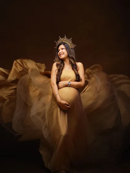A joyful and glamorous solo shot in a golden gown. The dynamic fabric toss and happy expression create a picture of pure celebration.