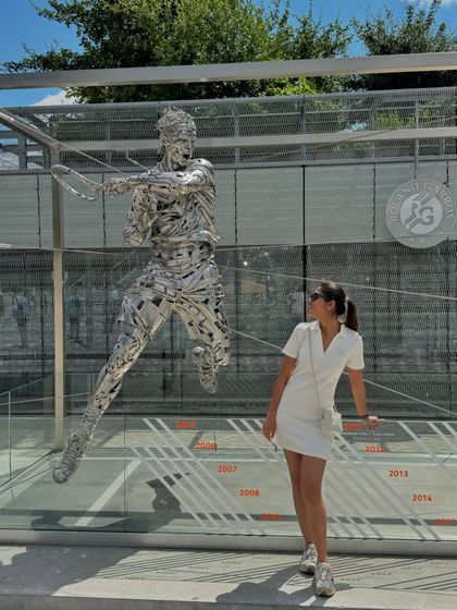 Posing next to the Rafael Nadal statue at Roland-Garros. My sporty-chic white dress and sneakers were the perfect tribute to a day of world-class tennis.