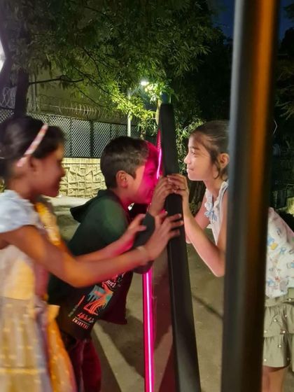 Children interacting closely with the illuminated frames of the 'Family Tree'. We design these installations to be durable and safe, encouraging tactile exploration and creating a multisensory experience.