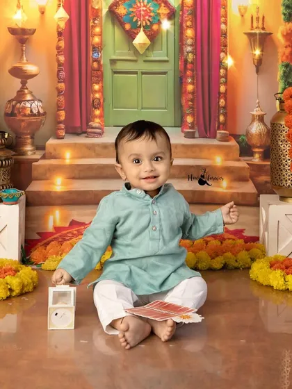 This little boy is all smiles during his Diwali mini session, playing with cards in a beautifully lit, traditional Indian setting.