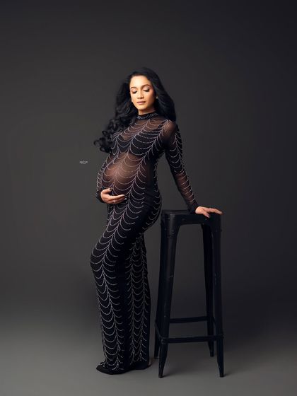 A full-length portrait showcasing the intricate detail of the embellished gown. It's a unique and edgy choice for a maternity glamour shoot.