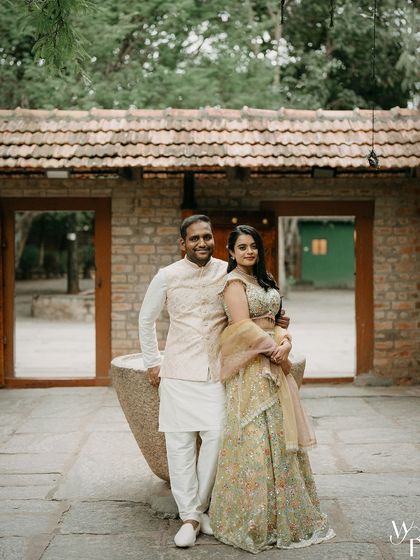 A formal portrait of a couple in front of a stone urn, their elegant outfits contrasting beautifully with the rustic texture of the walls.