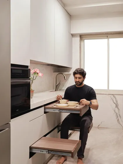 In a compact city kitchen, every inch matters. We integrated a retractable breakfast table and seating directly into the drawer system of this Project Acropolis kitchen, providing a convenient dining spot that disappears when not in use to maximize space.