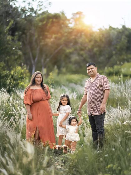 A happy family of four taking a walk through nature. The coordinated outfits in earthy tones complement the outdoor setting perfectly.