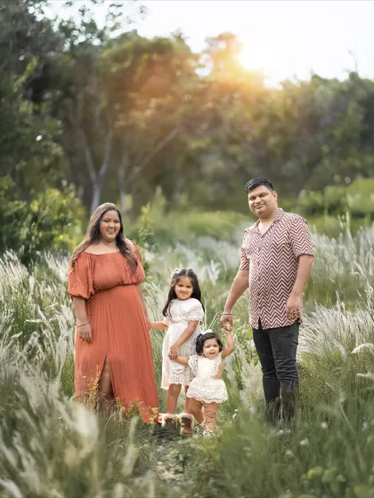 A family of four holding hands and walking through a field of tall, feathery grass at sunset. This creates such a dreamy and adventurous feeling.