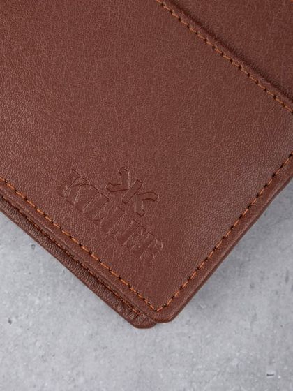 A close-up macro shot of the embossed brand logo on a brown leather wallet, highlighting quality.