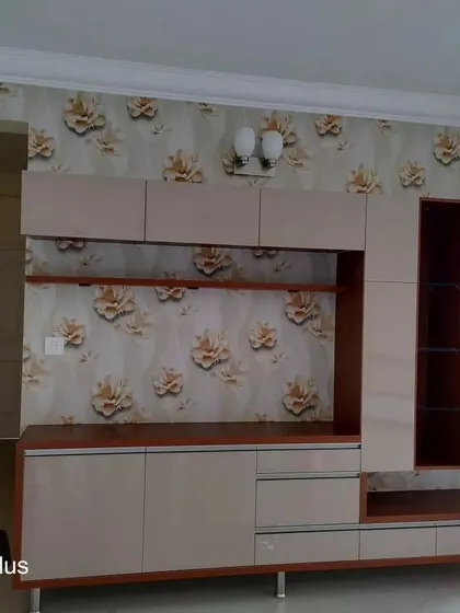 A floral wallpaper with large, golden-brown flowers installed behind a custom entertainment unit. This demonstrates how patterned wallpaper can complement and enhance wooden furniture.