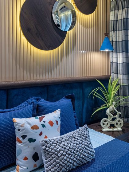 A wider view of the blue bedroom, showing the interplay of textures and patterns, from the striped curtains to the terrazzo-print cushion. It's a harmonious blend of colors and elements.