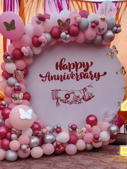 I can create custom themes for any celebration. This first-anniversary backdrop features a soft pink and silver color palette, a full balloon arch with butterfly details, and a light-up number '1' for a unique touch.