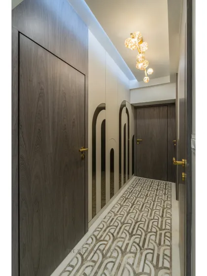 Another view of the elegant passageway, highlighting the contrast between the dark wood doors and the light-colored walls and floor. The design creates a sense of rhythm and flow.