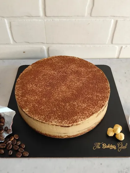 A simple yet elegant Tiramisu cake, ready to be delivered. The coffee and hazelnut props hint at the delicious flavors inside.