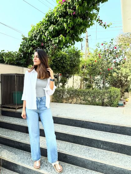 The art of wearing basics is anything but basic. A simple grey tank top, a crisp white shirt, and well-fitting light-wash jeans create a timeless, minimal, and effortlessly chic look for any day.