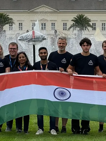 The entire team posing with the Indian flag, all wearing their custom-designed T-shirts.