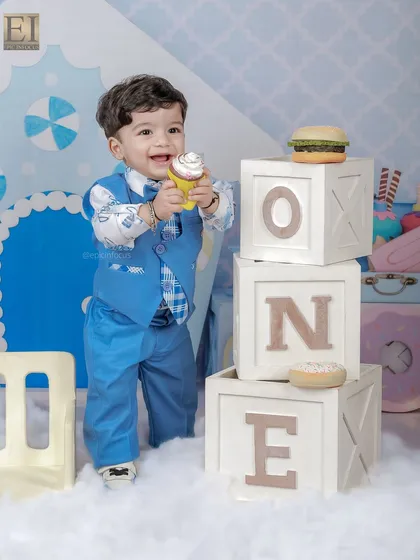 Standing tall next to the 'ONE' blocks, this little boy enjoys a prop cupcake in our sweet shop setup. We use a variety of props to keep children engaged and happy during the shoot.