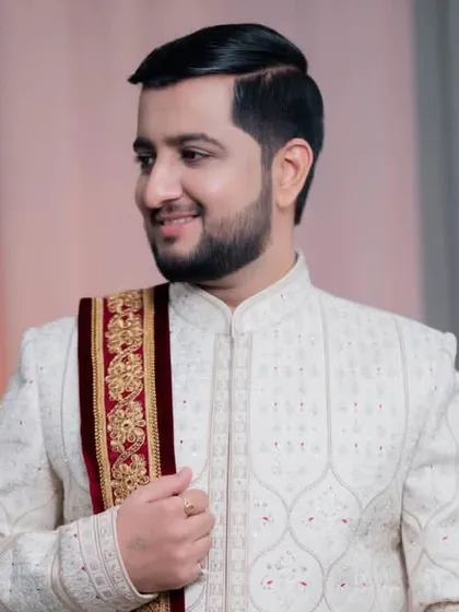 A side profile of the groom, highlighting the elegant drape of his shawl and the clean lines of his hairstyle.