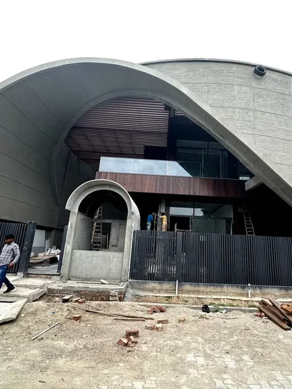 This modern monolith in Haryana is a cavernous family home defined by its striking exterior. The massive, curved concrete roof shell sweeps over the structure, creating a powerful and protective architectural statement that is both modern and primal.