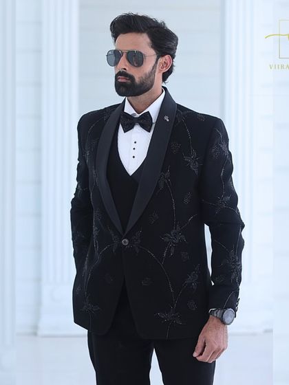 A confident pose in the embroidered black tuxedo, a perfect look for a reception.