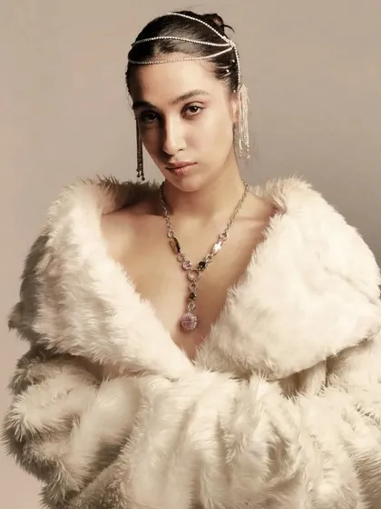 A close-up on the intricate hair jewelry and the soft, glowing makeup. The look is all about texture, from the fur coat to the sparkling accessories.