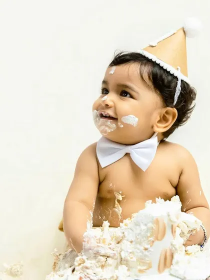 The pure, unfiltered joy of a first birthday cake smash. This little one's happy, frosting-covered smile is what these celebratory sessions are all about.