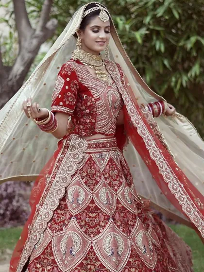 This red bridal lehenga features beautiful peacock motifs and intricate threadwork. The double dupatta style adds an extra layer of grace, and the entire set is available to rent for your wedding.