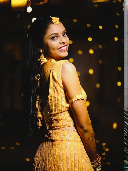 A lovely portrait of the bride looking back over her shoulder. The bokeh from the background lights adds a magical touch to her Haldi look.
