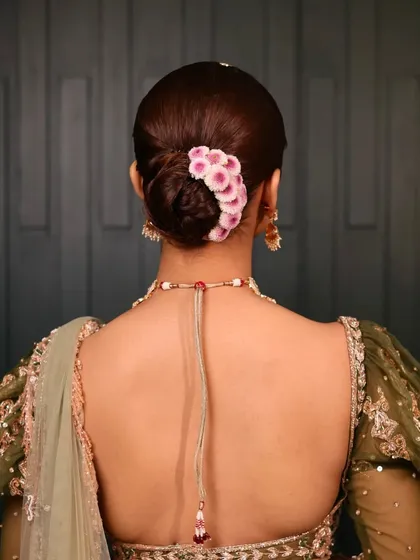 The back view of this modern floral bun. The placement of the flowers adds a pop of color and a touch of romance to the otherwise sleek and classic hairstyle.
