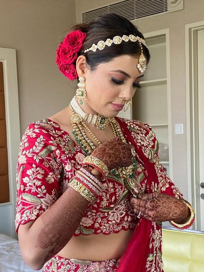 A beautiful bridal bun adorned with fresh red roses. This is a classic and romantic choice that pairs perfectly with a traditional red lehenga.