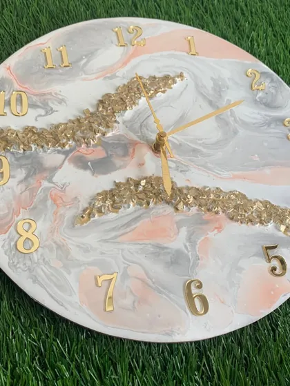 A soft and elegant clock with a grey and pink marble design, accented with bands of gold crystals.