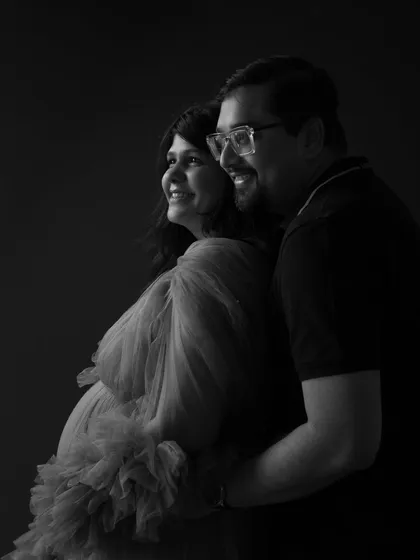 Looking towards the light, together. This black and white portrait uses chiaroscuro lighting to create a dramatic, cinematic feel. Their hopeful expressions and close embrace tell a story of love and optimism.