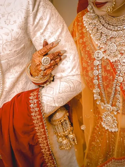 A close-up on the intricate details of the bride and groom's wedding attire. The rich colours and heavy embroidery are an essential part of the wedding story.