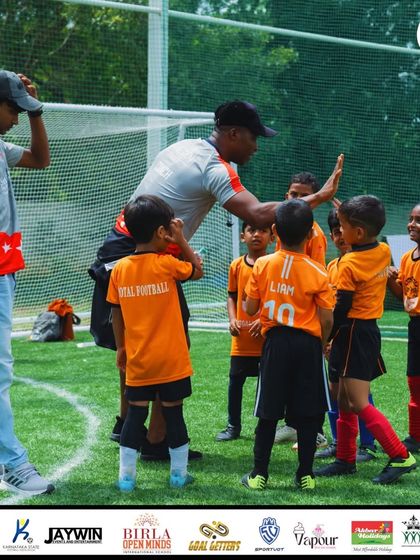High-fives all around! A coach celebrates with his young team, fostering a positive and fun atmosphere.