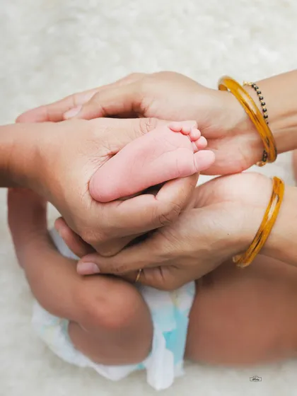 A close-up of a newborn's tiny foot held gently in their mother's hands. We focus on these small details that you will want to remember forever.