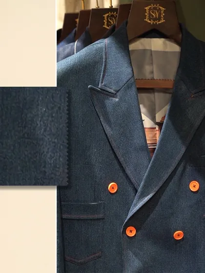 A close-up of the double-breasted denim blazer with a fabric swatch. This allows you to see the texture of the denim and the craftsmanship of the garment.