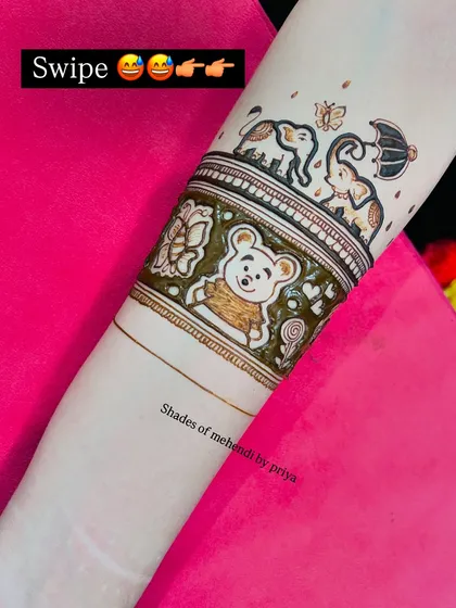 The initial outline of the cute motifs on the forearm for a baby shower mehendi, including a teddy bear and playful elephants.