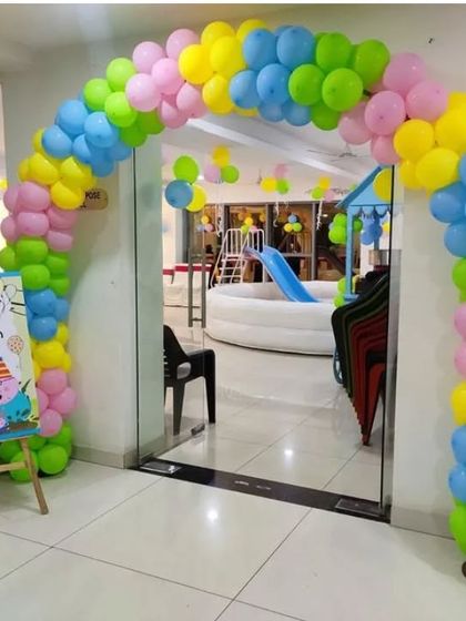 A cheerful Peppa Pig themed entrance arch for a 4th birthday party. The bright, multi-colored balloon arch and personalized welcome sign create a fun entry point for a kids' play area.