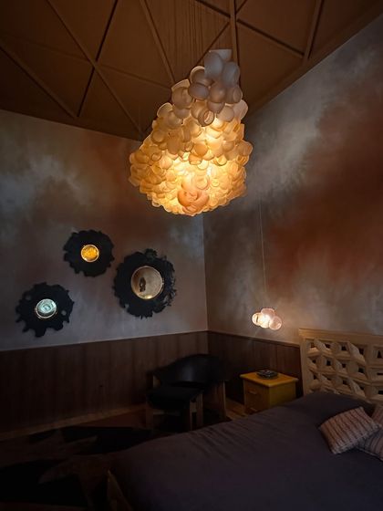 The Bocci 100 series installed in a bedroom at the Bocci Milan Apartment. The cloud-like formation adds a soft, ethereal quality to the room's moody and artistic decor.