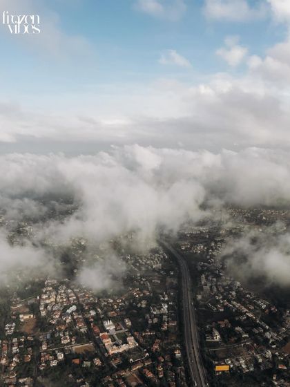 An aerial shot of the city covered in clouds. This atmospheric shot helps to build a cinematic narrative for the wedding film or album.