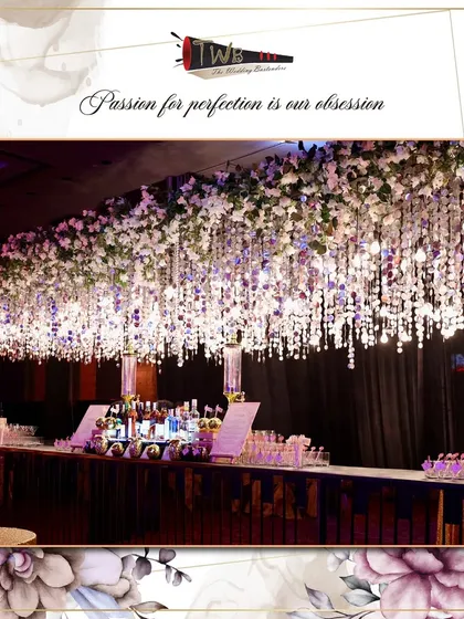 A grand and elegant bar setup for a Sangeet at Sahara Star, featuring a stunning overhead installation of white flowers and cascading crystals that exudes luxury and sophistication.