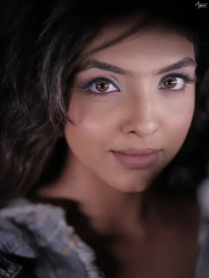 This is a pure beauty portrait, where the eyes tell the story. The tight crop and soft lighting put all the emphasis on the stunning eye makeup and the subject's direct, captivating gaze.