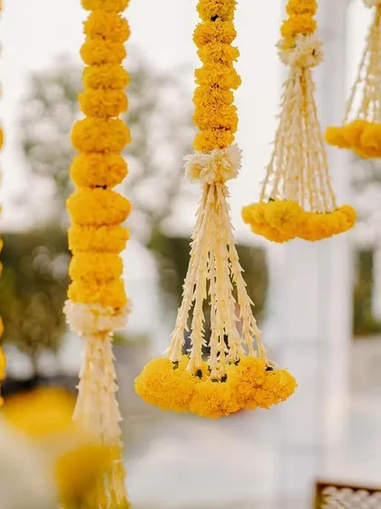 A close-up of the delicate hanging garlands of marigold and tuberose, showcasing the intricate craftsmanship that goes into our floral decor.