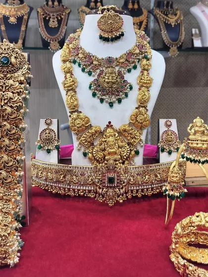 This grand temple jewellery set is a complete bridal solution. It features a Ganesha motif long haram, a choker, matching earrings, a maang tikka, armlets (vanki), a hip belt (oddiyanam), and a full hair accessory (jada billai) for a divine bridal look.