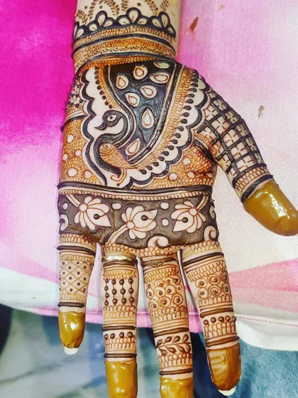 A close-up of a single hand, showing a detailed peacock motif and intricate finger designs.