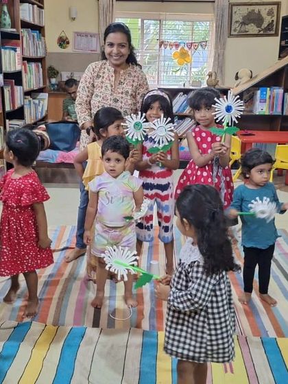 The storyteller and children pose with the paper flowers they made, a bright and cheerful end to the session.
