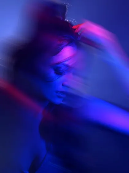 An abstract portrait where the model's face is obscured by motion and colored light. This shot is purely about mood and energy, pushing the boundaries of conventional portraiture.