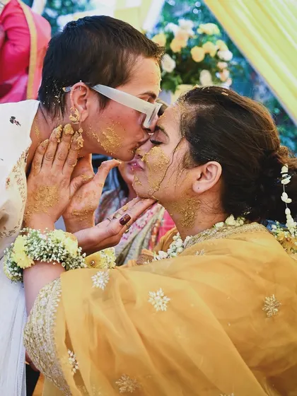 A sweet kiss shared during a Haldi ceremony. This photo captures a moment of love and fun amidst the joyful chaos of the pre-wedding rituals.